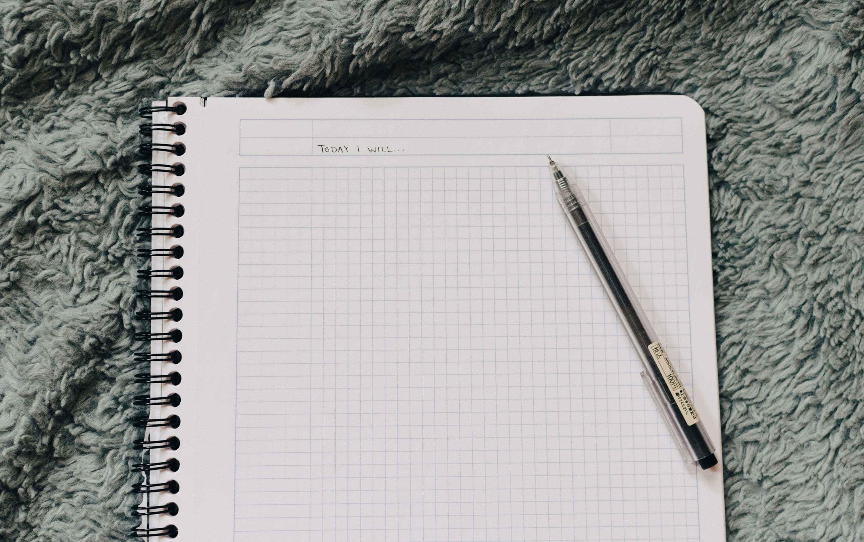 a notebook with a pen on top of a fuzzy blanket