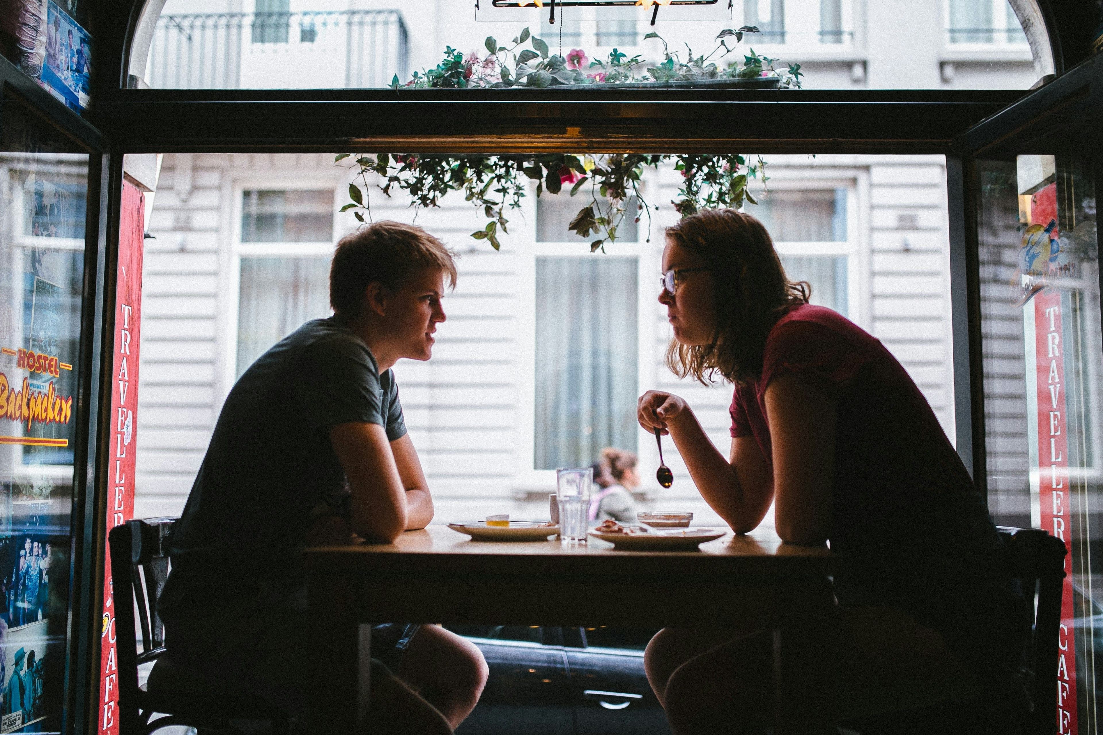 a man and a woman sitting at a table in front of a window